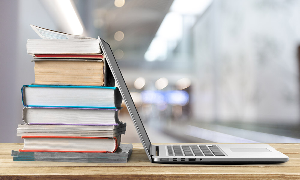 Stack of books with laptop on wooden table Stack of books with laptop on wooden table
